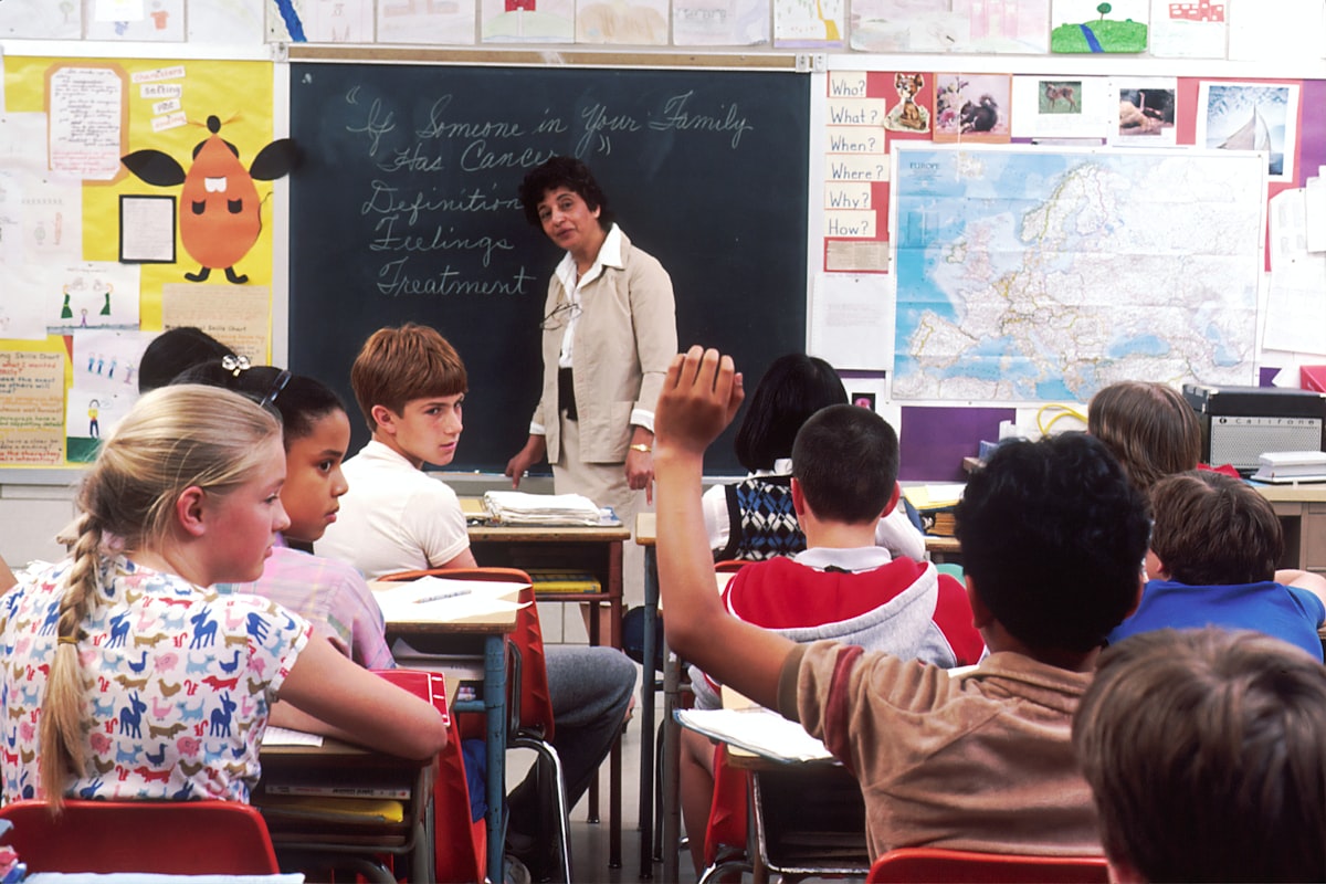 A smiling teacher working with young students
